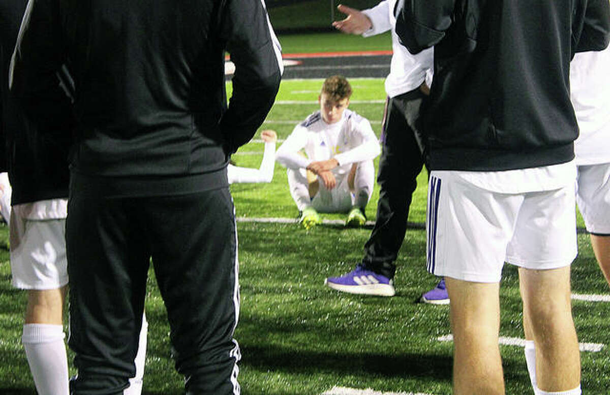 Bryce Davis of Civic Memorial sits dejectedly on the turf at Triad and listens to post-game remarks from Eagles coach Derek Jarman. CM lost to Mascoutah 3-2 in a semifinal of the IHSA Class 2A Triad Sectional tournament Tuesday night.