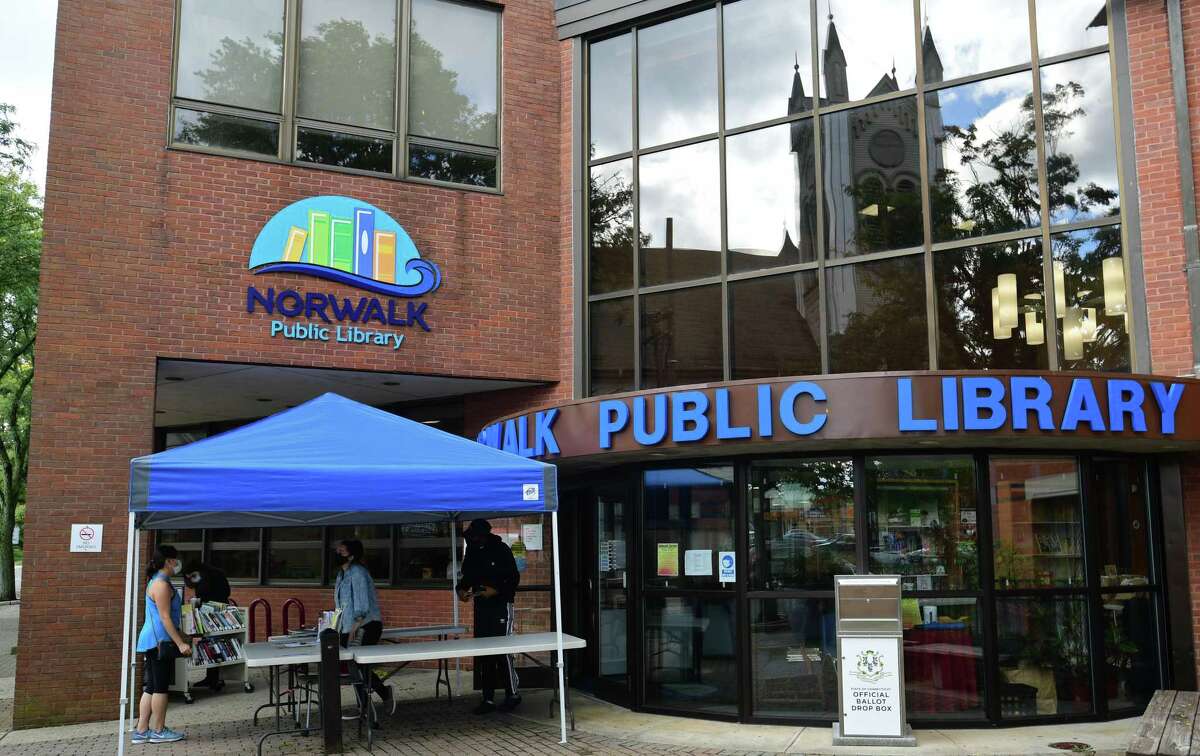 Norwalk Public Library employees help patrons during the sidewalk service option offered weekdays at the main branch Wednesday, September 30, 2020, in Norwalk, Conn.