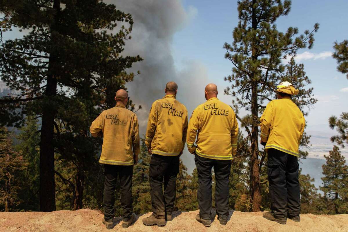 Firefighters observe a growing blaze from Janesville Grade Road near Janesville, Calif. The storms that battered Northern California in recent days did not drop enough rain for Cal Fire to officially declare an end to fire season.