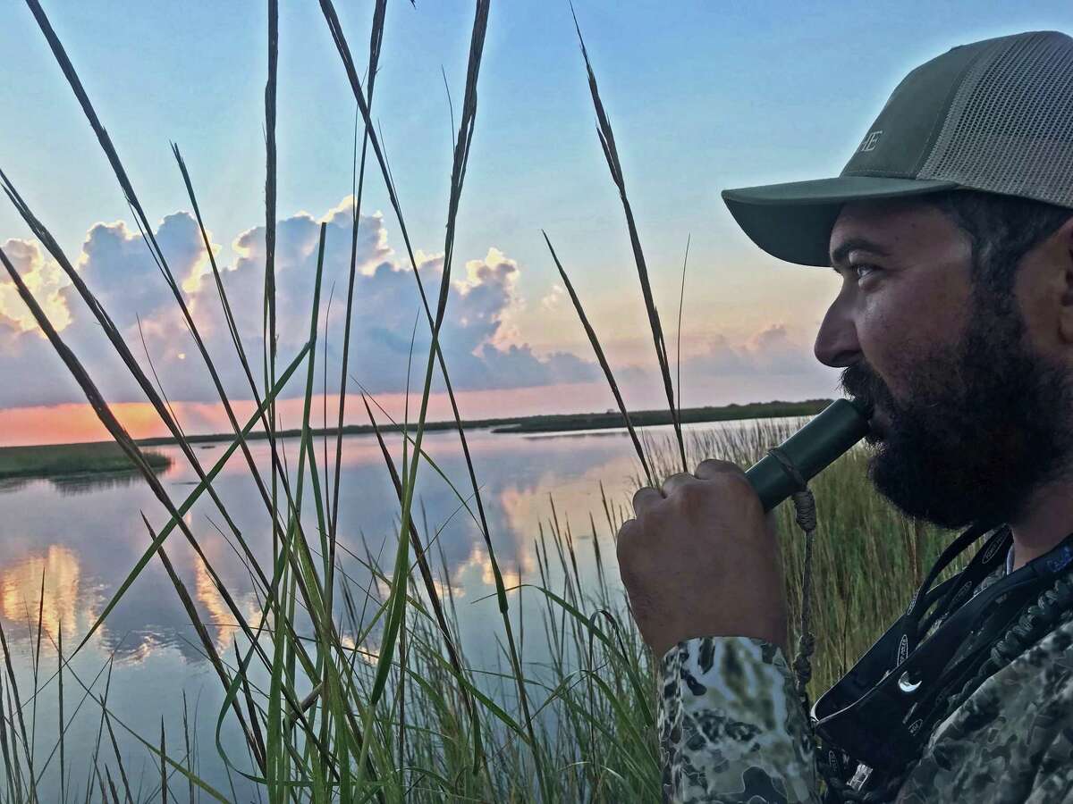 Capt. Jared McCulloch, who uses an airboat to reach really shallow waters near Rockport such as this lake near Vinson Slough, blows on a duck call at daybreak.