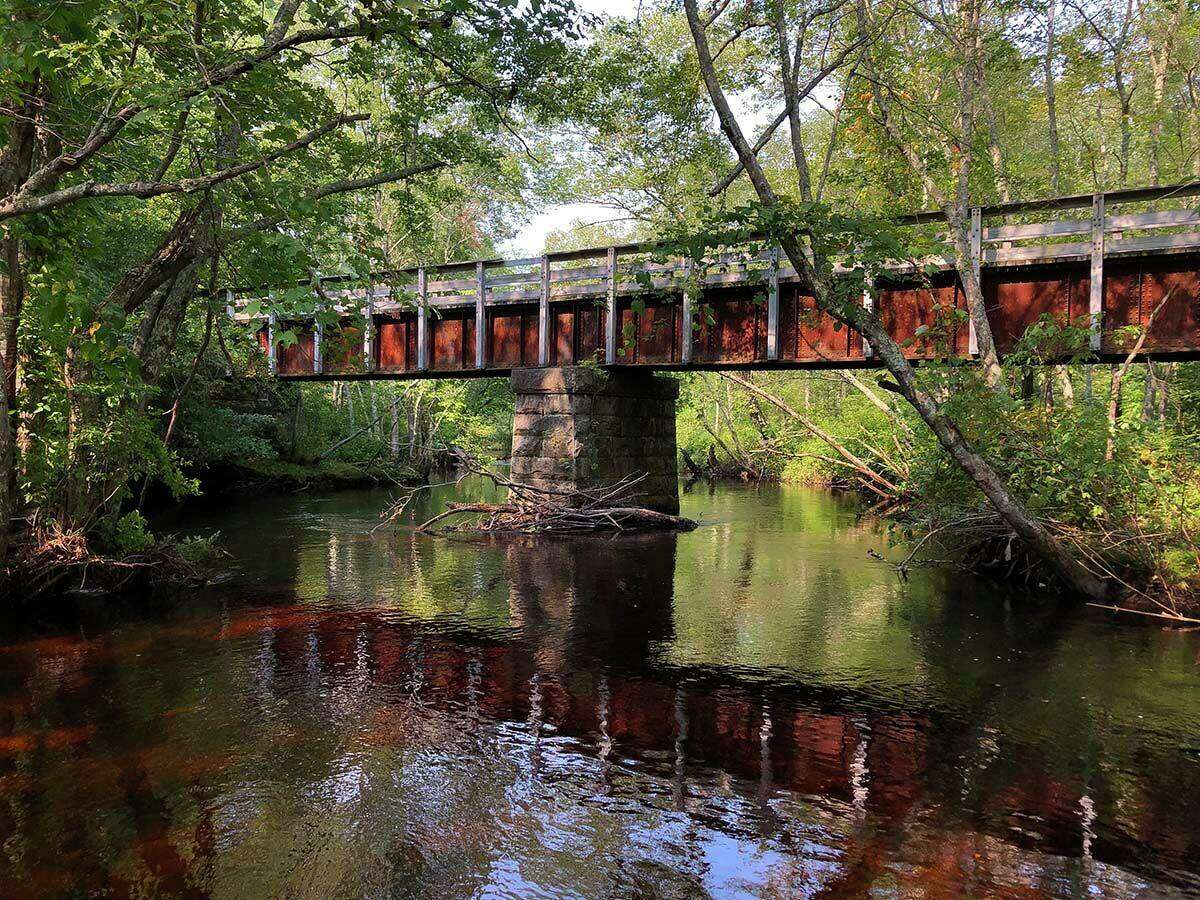 A railroad bridge reflects off the waters of the Moosup River in Connecticut.