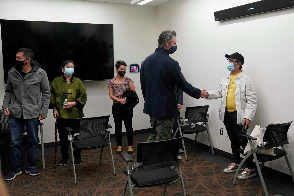Gov. Gavin Newsom (second from right) greets other patients Wednesday before receving a Moderna booster shot at Asian Health Services in Oakland.