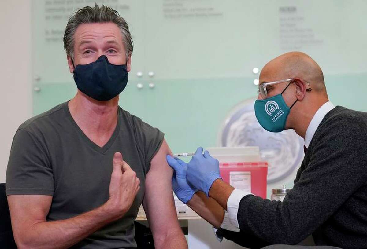 California Gov. Gavin Newsom (left) receives a Moderna booster from state Health and Human Services Secretary Dr. Mark Ghaly at Asian Health Services in Oakland.