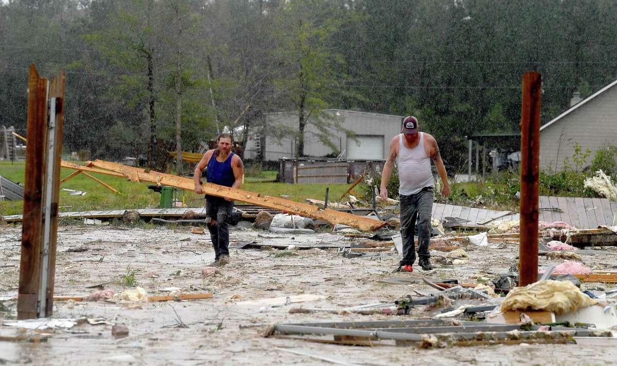 Men carrry out debris from behind a damaged home in the Sandy Oaks subdivision in Hartburg. Homes and properties in Orange and Newton Counties were damaged after a powerful tornado ripped through the area amid heavy storms Wednesday. Photo made Wednesday, October 27, 2021 Kim Brent/The Enterprise