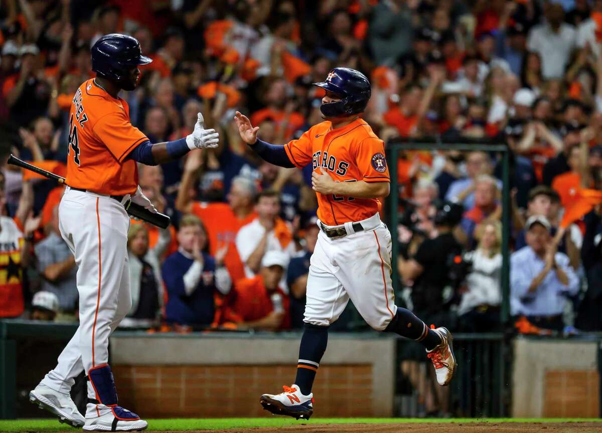 Houston Astros second baseman Jose Altuve (27) is welcomed at home by Houston Astros designated hitter Yordan Alvarez (44) after being driven home on a sacrifice fly by Houston Astros third baseman Alex Bregman (2) to give the Astros a 1-0 lead during the first inning in Game 2 of the World Series on Wednesday, Oct. 27, 2021 at Minute Maid Park in Houston.