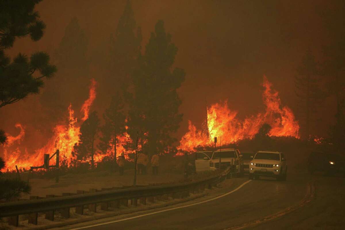 Flames rush uphill behind cars stopped on Highway 50 as the Caldor Fire continued its march toward Meyers, Calif., on Monday, August 30, 2021.
