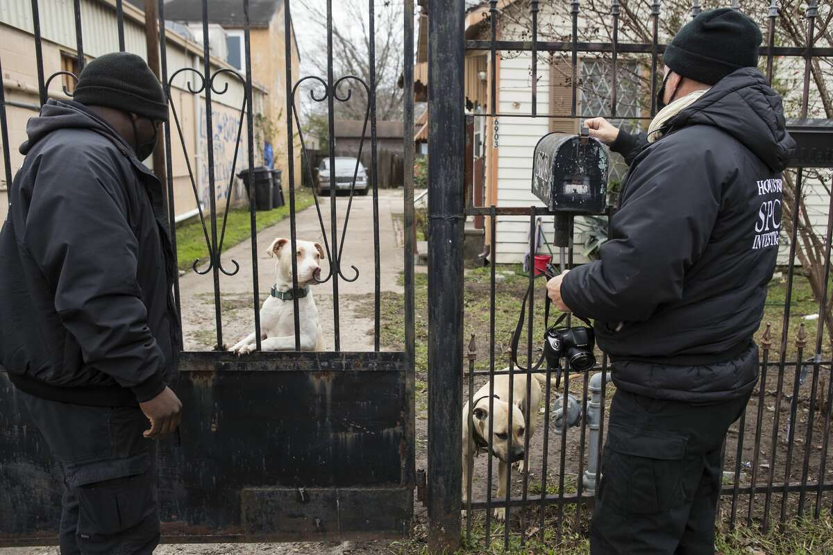 Society for the Prevention of Cruelty to Animals investigators D'Questyn Coleman, left, and Jay Chase check on a pair of dogs that were reported to be chained up outside of a house during  inclement weather on Feb. 13, 2021, in Houston. 