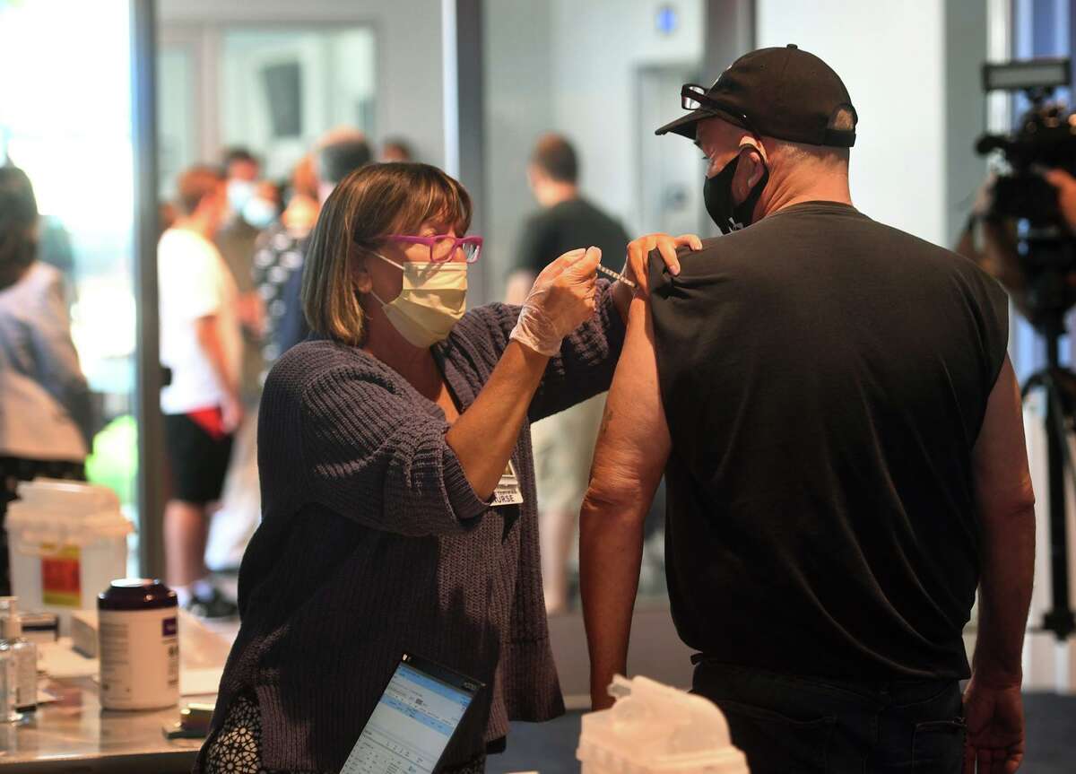 A nurse administers a COVID-19 vaccination in August 2021 to a truck driver in Bridgeport, Conn.