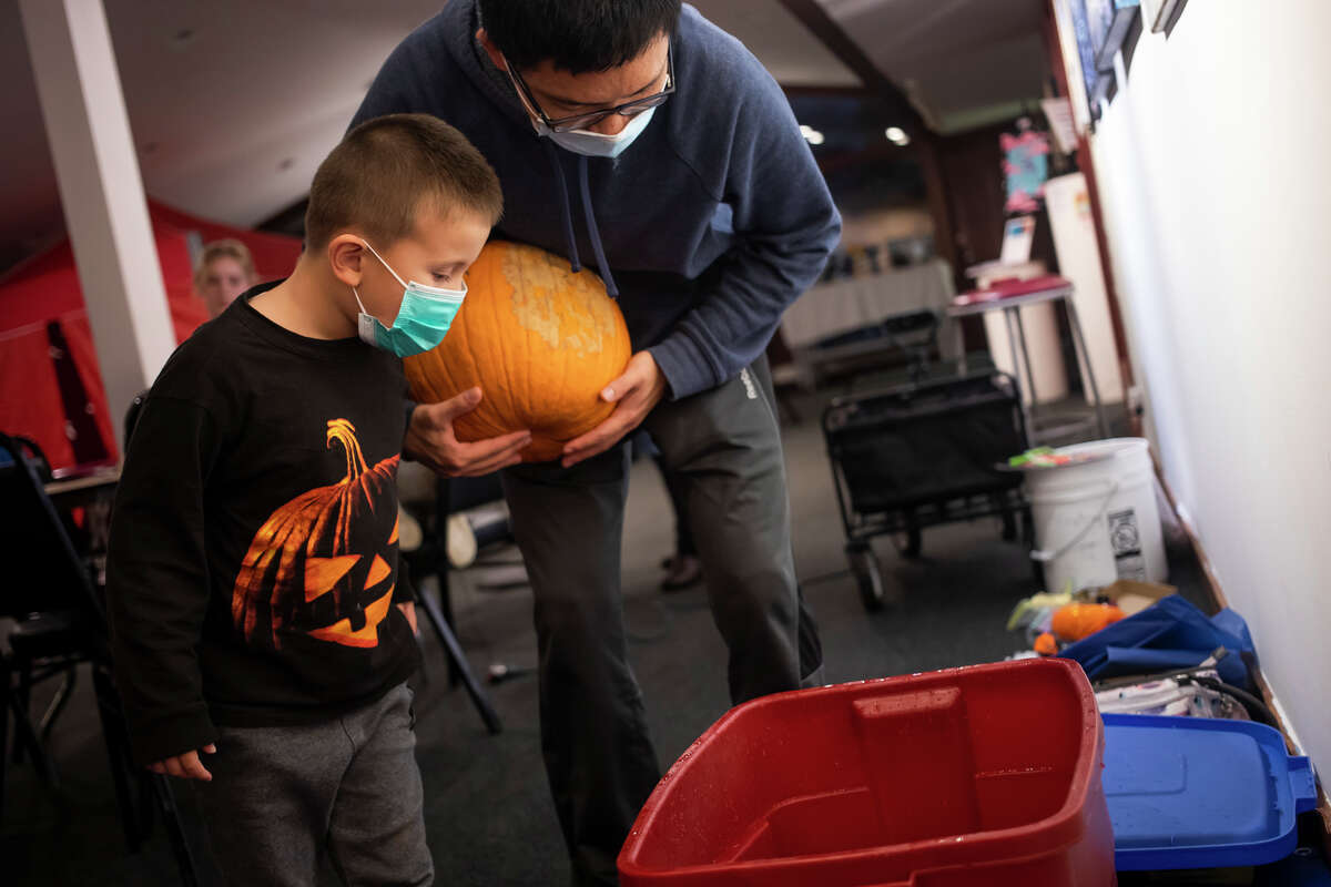 Hanze Ying, center, and his son Tango Ying, 5, test the buoyancy of different pumpkins as families enjoy games, snacks and pumpkin decorating during an event Wednesday, Oct. 27, 2021 at Creative 360 in Midland. (Katy Kildee/kkildee@mdn.net)