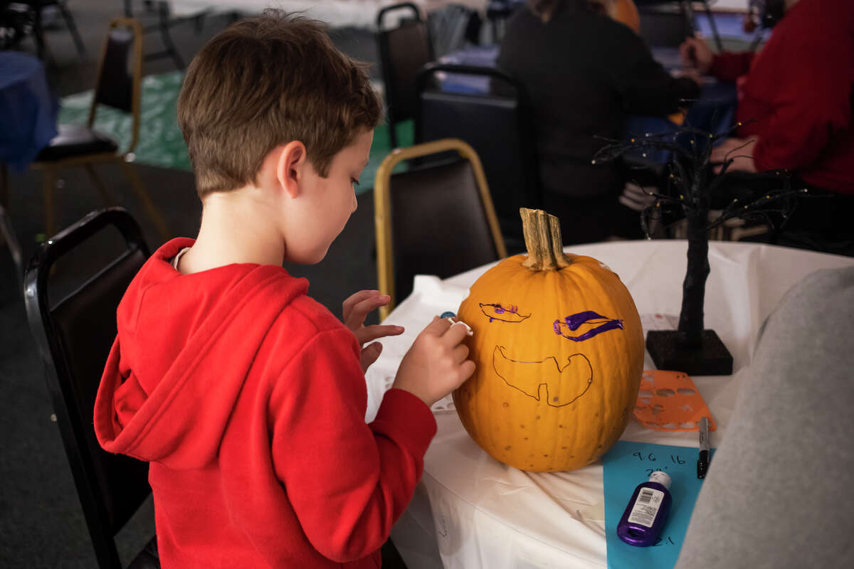 Lorenzo Bayardo, 6, center, decorates a pumpkin as families enjoy games, snacks and pumpkin decorating during an event Wednesday, Oct. 27, 2021 at Creative 360 in Midland. (Katy Kildee/kkildee@mdn.net)