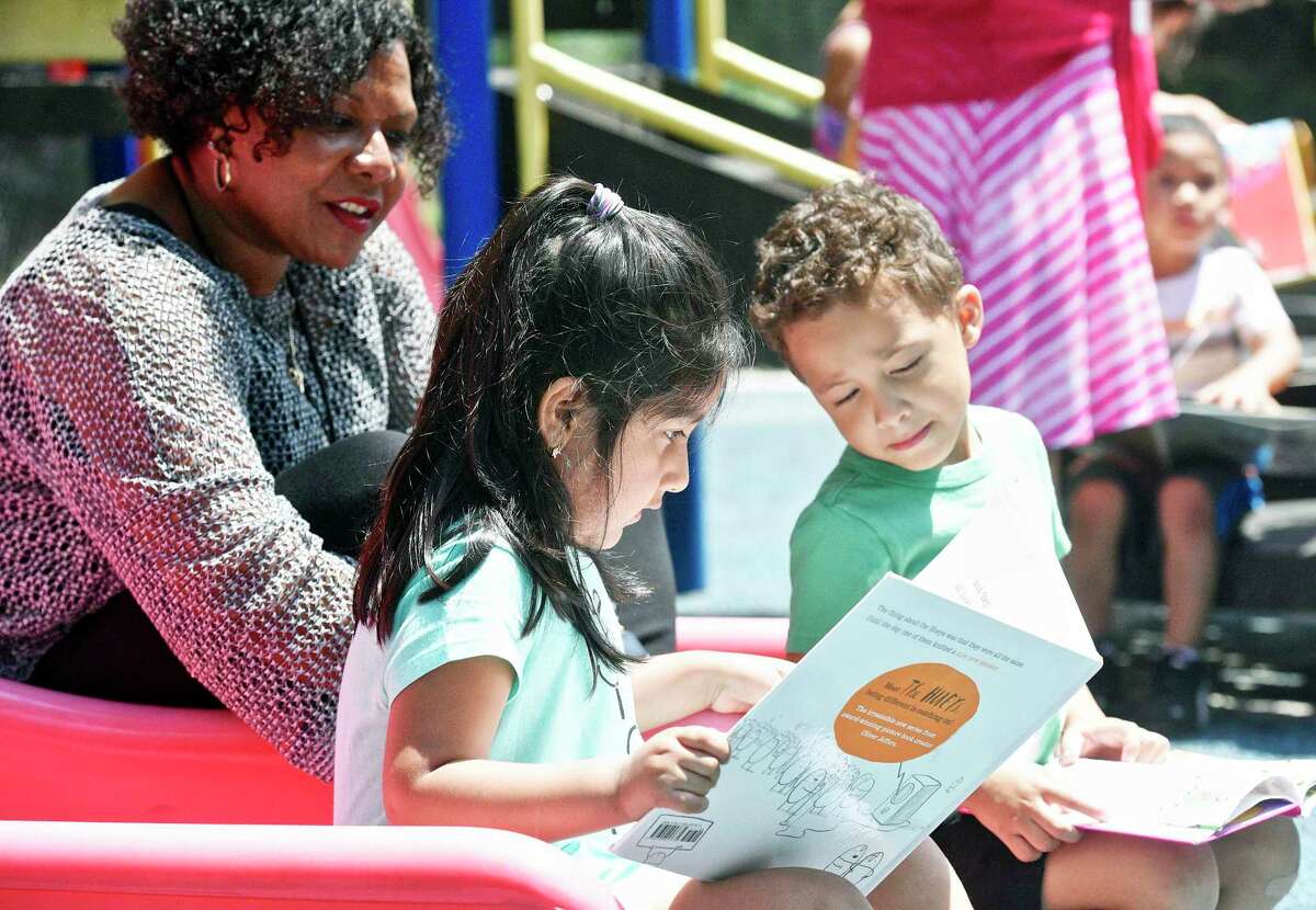 Emily Arials reads a book as Kauan Neves looks on at the Action Early Learning Center, in Danbury. Michelle James, executive Director of Community Action Agency of Western Connecticut follows along.