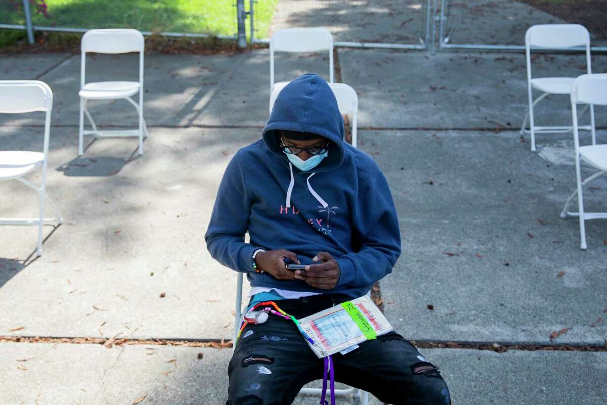Oakland Tech student Daylon Perkins, 17, sits for the 15-minute waiting period after receiving his COVID-19 vaccine.