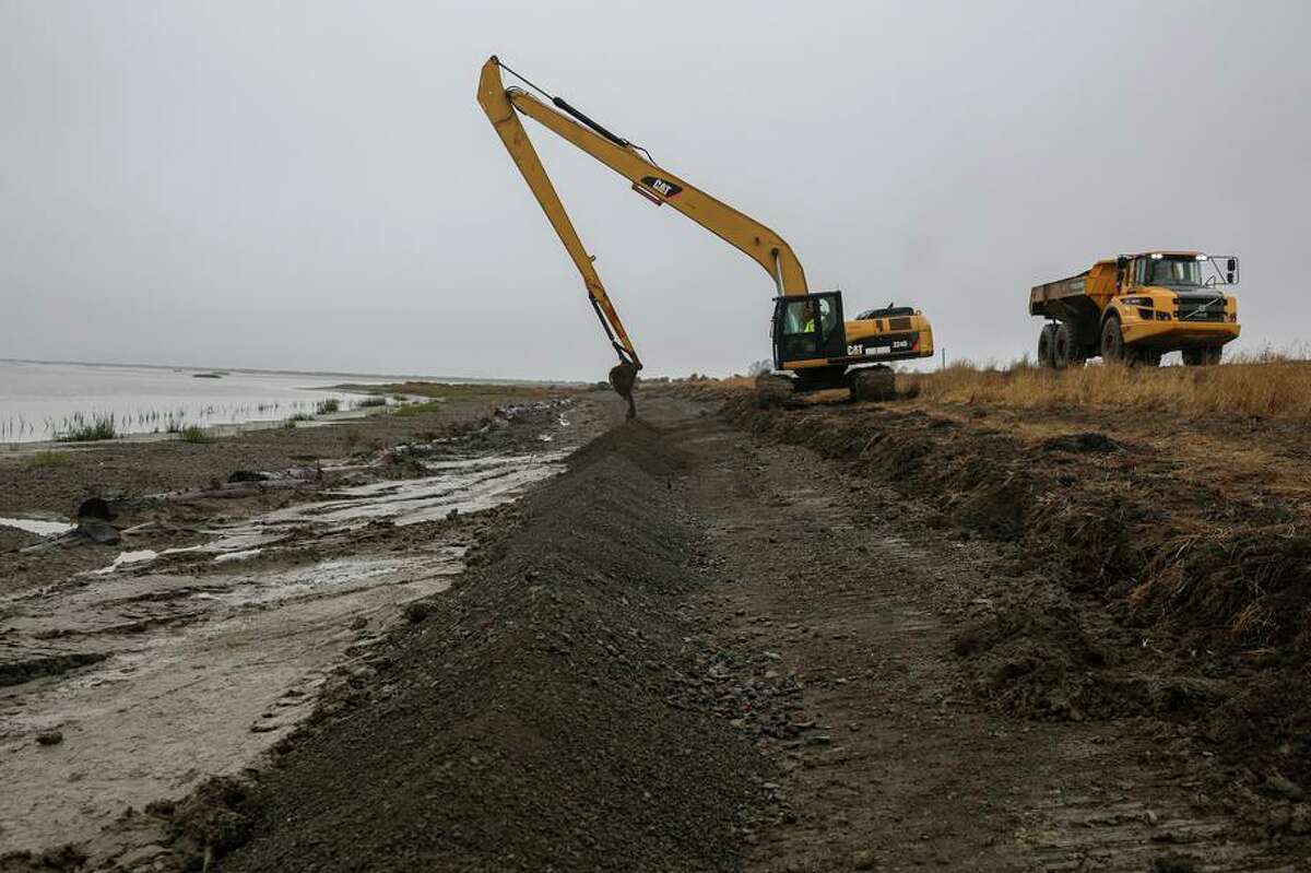 A worker uses an excavator to place recycled gravel near an eroding levee at Sears Point Ranch on San Pablo Bay. The Sonoma Land Trust is experimenting with natural materials to create protective barriers to allow important marsh plants such as Pacific cordgrass and pickleweed to grow.
