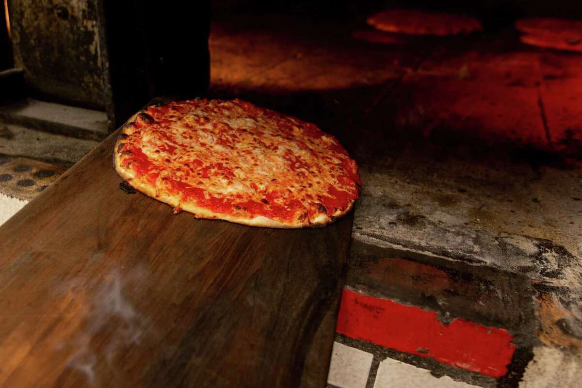 In this file photo, and example of a hot pizza being pulled out of the oven. This is at Sally's Apizza in New Haven on April 23, 2021.