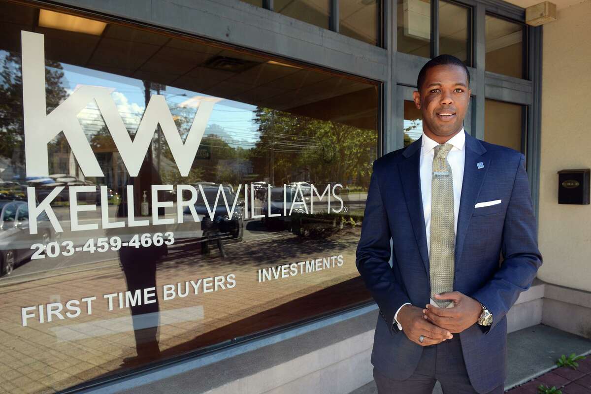 Real estate broker Daniel Thomas poses in front of the Keller Williams Realty office in Stratford, Conn. Sept. 20. 2021.