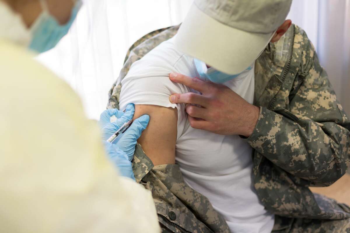 FILE - A doctor injects the COVID-19 vaccine in the arm of a young military soldier. 