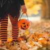 A trick-or-treater in costume walking through leaves.