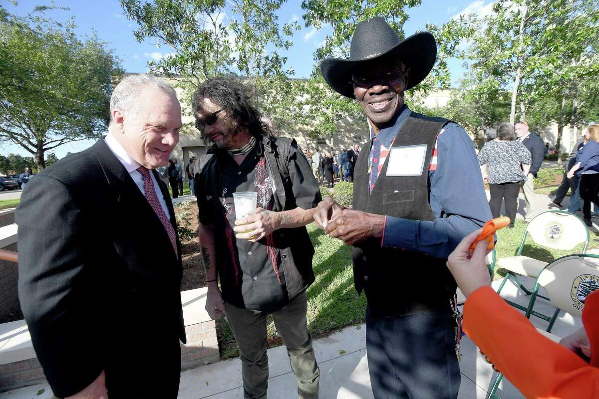 Lamar State College Orange President Tom Johnson talks with Brown family friend Billy Andrews as Bobby Brown, Gatemouth's brother, is offered a piece of the ribbon during the opening celebration for the campus' new Gatemouth Plaza Thursday. Photo made Thursday, October 28, 2021 Kim Brent/The Enterprise
