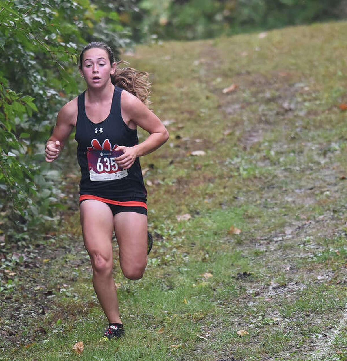 Edwardsville’s Olivia Coll, left, runs down a hill during the Southwestern Conference Meet.