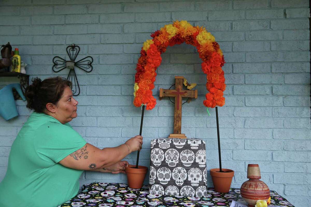 Yvette Gonzales sets up her altar for Dia de Los Muertos, Tuesday, Oct. 26, 2021. Gonzales started the tradition in 2009 soon after her sister, Hilda Garza, died, leaving behind five young children. She did it so they would remember their mother. Gonzales also honors her mother and grandparents with the altar.