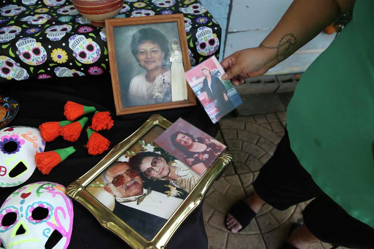 Yvette Gonzales uses photographs of deceased relatives on her altar for Dia de Los Muertos, Tuesday, Oct. 26, 2021. Gonzales started the tradition in 2009 soon after her sister, Hilda Garza, died, leaving behind five young children. She did it so they would remember their mother. Gonzales also honors her mother and grandparents with the altar. She holds a photo of her mother, Alicia Rodriguez. Her sister?•s photograph is center with her grandparents, Vicente and Theresa Orta, photograph in the frame.