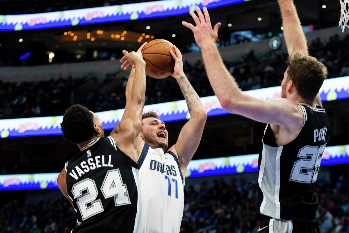 Dallas Mavericks guard Luka Doncic (77) drives toward the basket as San Antonio Spurs guard Devin Vassell (24) and center Jakob Poeltl (25) defend during the first half of an NBA basketball game Thursday, Oct. 28, 2021, in Dallas. (AP Photo/Sam Hodde)