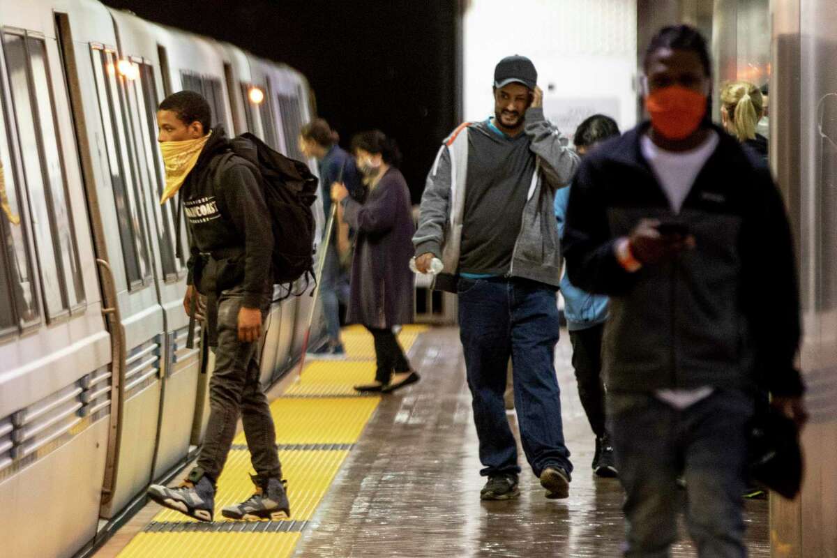 Riders wear face masks while waiting for their trains at Powell Street BART Station in in San Francisco, Calif. Friday, June 26, 2020. People returning to public transportation can expect mandatory face coverings for riders and operators, physical distancing markers and limited capacity on all vehicles. BART has a 15-step plan to welcome back riders that includes using hospital-grade disinfectant in stations and on-board trains, running longer cars to help promote social distancing, and offering personal hand straps for purchase that riders can take home and wash.