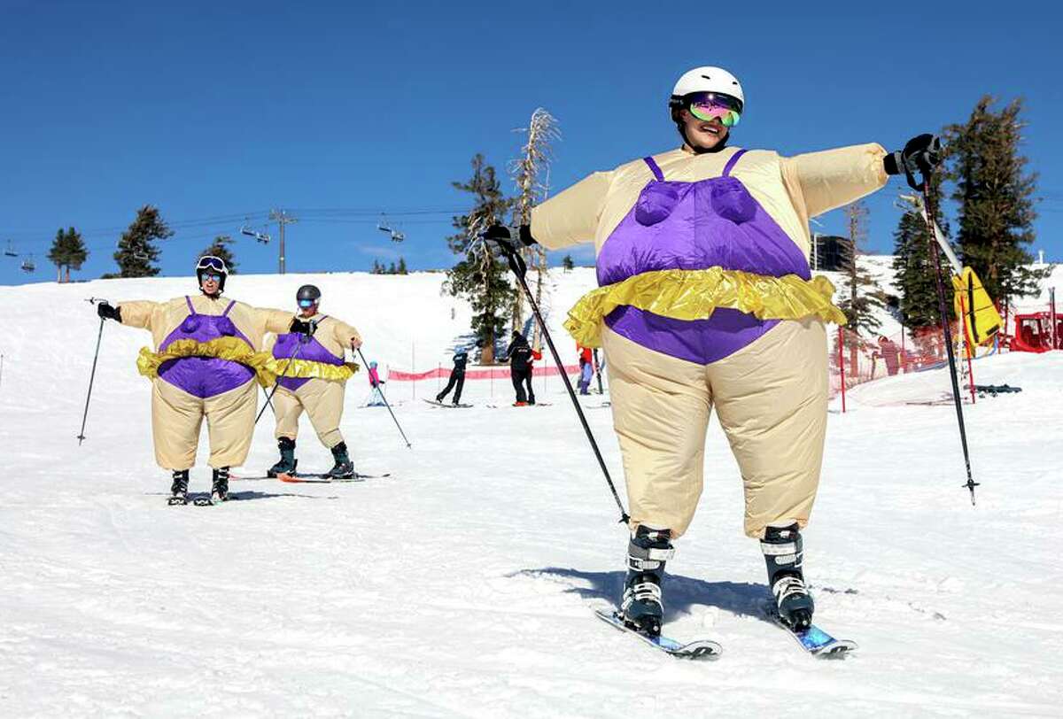 Joint caption: Top: Katie Muelle, center, toasts to opening day with her friends Brian Stanish, left, and Stephanie Moquin near Gold Coast Express at Palisades Tahoe in Olympic Valley, Calif. on Friday, Oct. 29, 2021. Above: Reno resident Alicia Werner skis in a Halloween costume with her friend Tori Yakstis, left, of Seattle, and husband Zach, right, during opening day at Palisades Tahoe in Olympic Valley, Calif. on Friday, Oct. 29, 2021. Not only is the ski resort opening under a new name, but this is the third time in its 72-year history that it’s had an opening day in October.