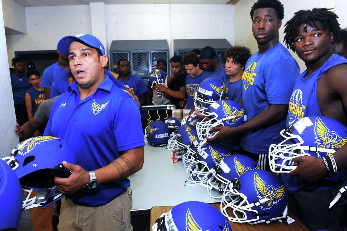 Head football coach Eddie Santiago meets with his team as they receive new helmets in preration for the upcoming season at Harding High School, in Bridgeport, Conn. Aug. 3, 2017.