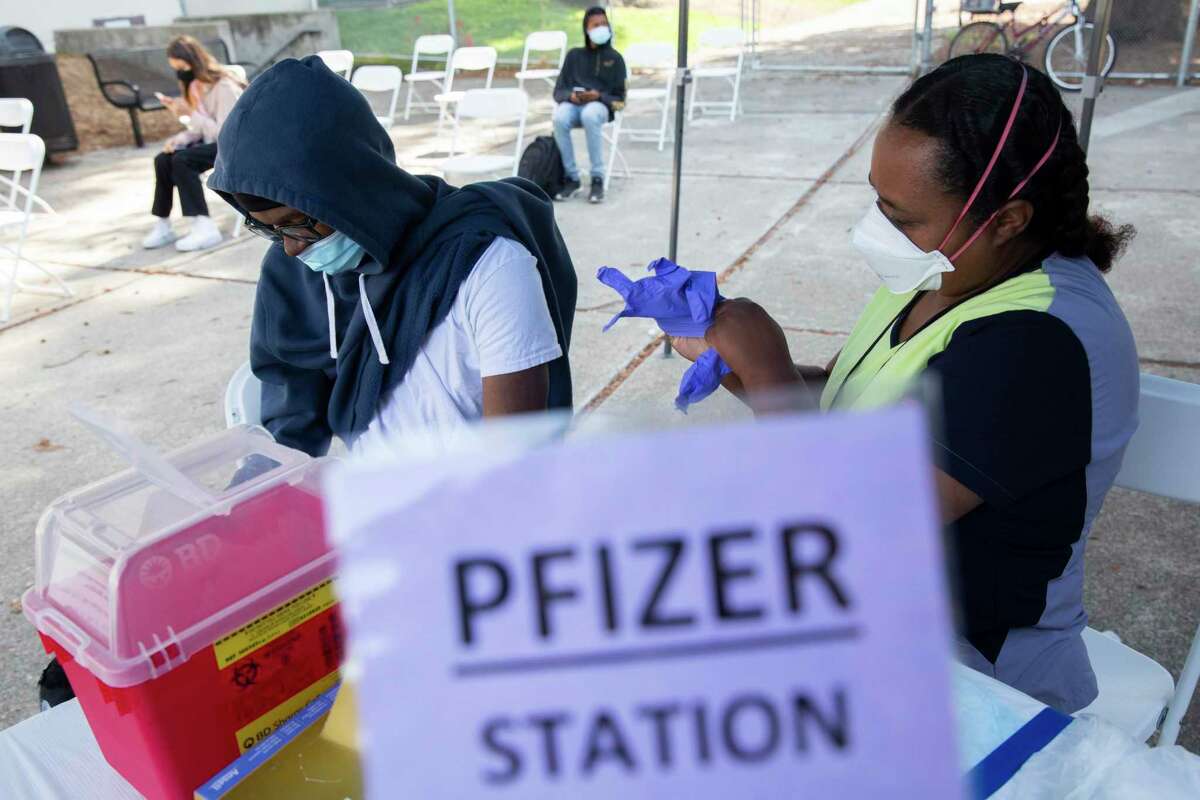 Alameda County Public Health registered nurse Emawayish Haile administers the Pfizer vaccine to 17-year-old Oakland Tech High School student Daylon Perkins at a vaccine clinic in September.