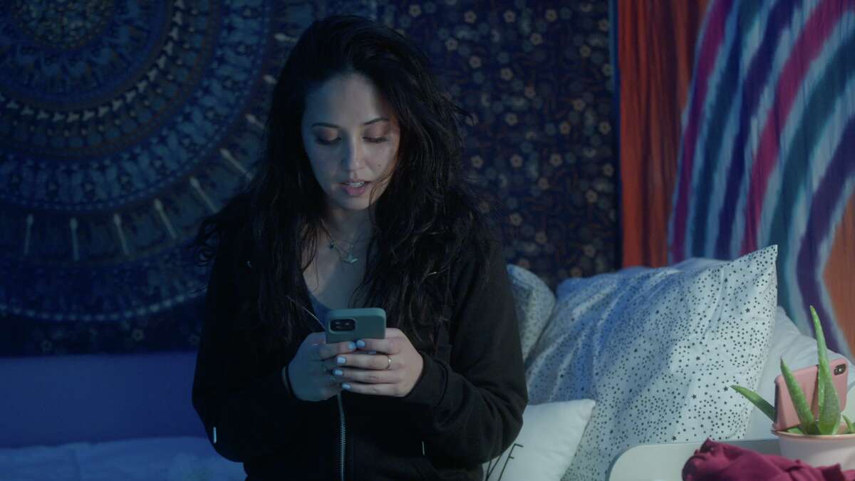 Roo Powell texting in a decoys bedroom in "Undercover Underage" on Discovery+.