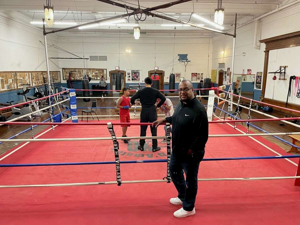 Kyle Lyles, director of Cus D'Amato Boxing Gym, Inc., stands on the boxing ring as Christian Jason trains two youths.