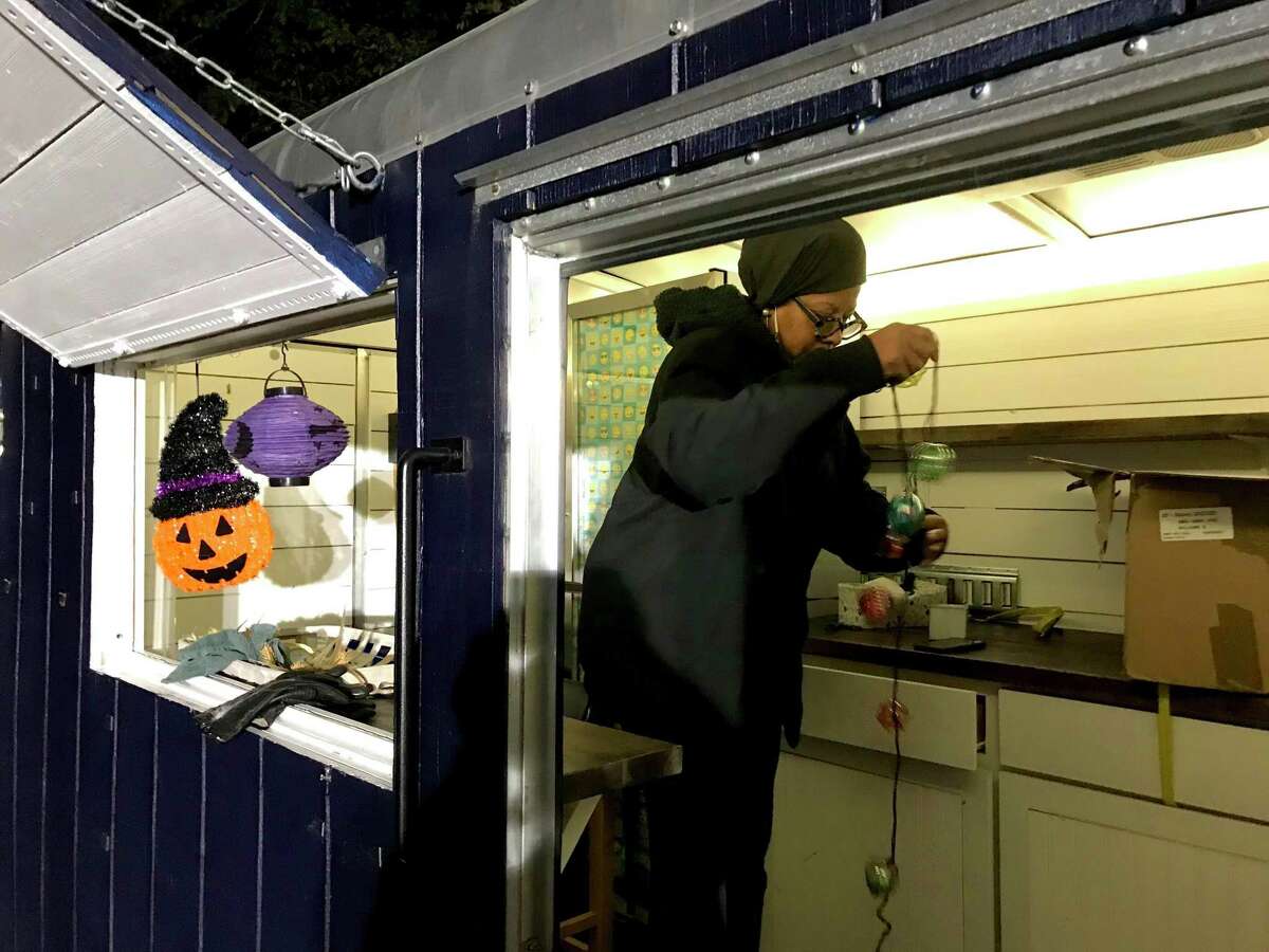 Kim Bianca Williams, a Bridgeport consultant and entrepreneur, dons a Halloween spider web with help from Rowena White, communications director for the city, at the annual Trunk 'n Treat event in Beardsley Park on Oct. 29, 2021.  Williams' gourmet popcorn trailer is at right; she is shown in the trailer after the event.