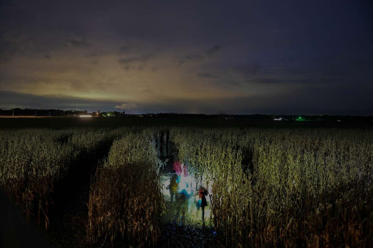 People navigate the muddy corn field at the final flashlight corn maze of the season on Saturday, Oct. 30, 2021 at Grandma's Pumpkin Patch in Midland. (Adam Ferman/for the Daily News)