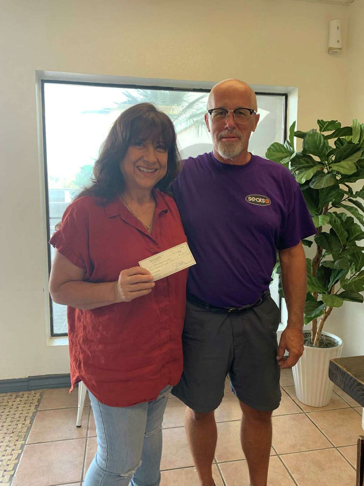 Jim Heuer, of Seats, Inc., presents a check for $1,000 to Mary Bender, of Pets Alive Laredo (PAL), on behalf of the W.R. & Floy A. Sauey Family Foundation.