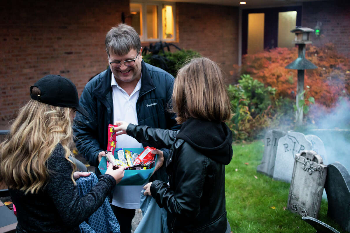 Jim Schutz, center, passes out candy bars as families go trick-or-treating Sunday, Oct. 31, 2021 in Midland. (Katy Kildee/kkildee@mdn.net)