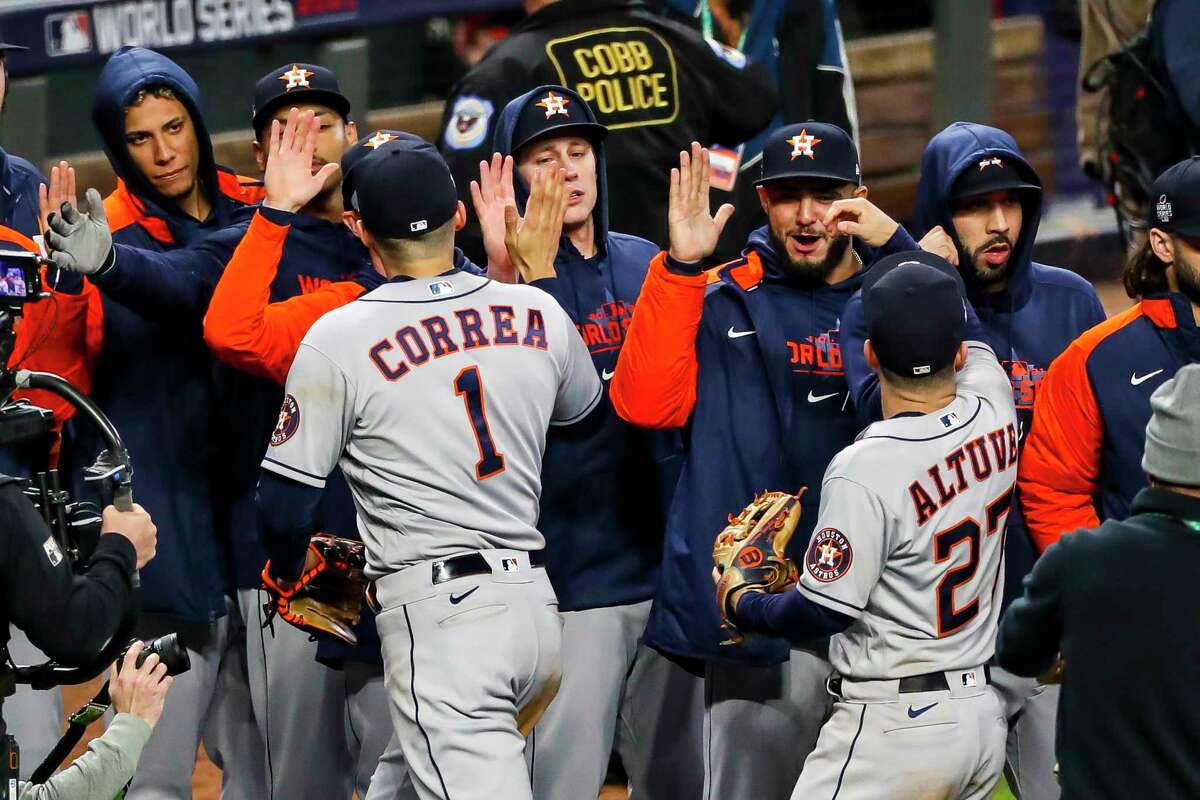 Houston Astros shortstop Carlos Correa (1) and Houston Astros second baseman Jose Altuve (27) high-five their teammates after winning Game 5 of the World Series on Sunday, Oct. 31, 2021 at Truist Park in Atlanta.