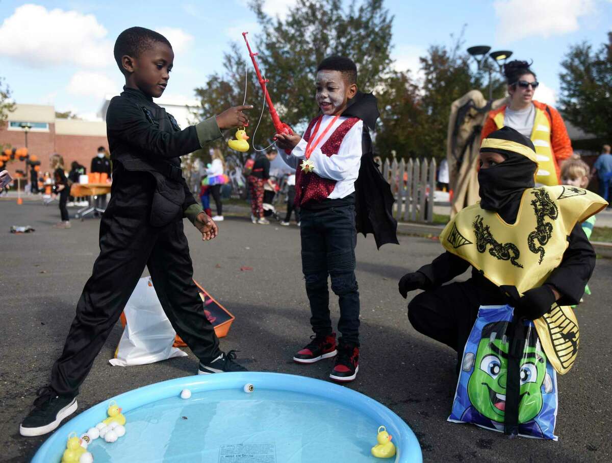 Stamford's Marklo Fuller, left, 6, Logan Domond, center, 5, and King Haywood, 8, go fishing at the Tech or Treat Halloween event at J.M. Wright Technical High School in Stamford, Conn. Sunday, Oct. 31, 2021. The spooky event featured a kids costume contest, pumpkin painting, game stations, spooky vignettes made by students, a DJ, and 'Bone' Appétit cafe.