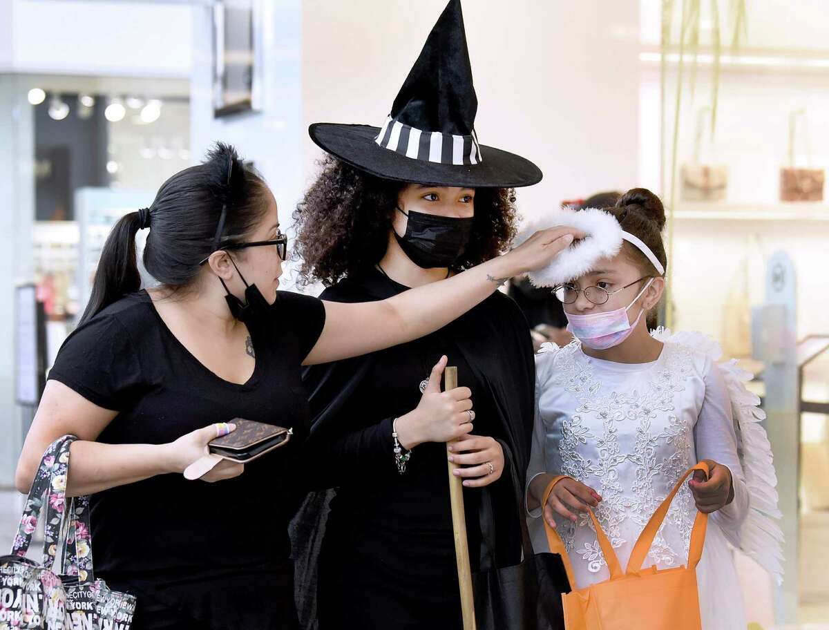 Jocelyn Villacres, left, adjusts the halo on her daughter Amara’s angel costume. Center is daughter Adrianna, 14, dressed as a witch. The Westfield Trumbull mall hosted a family-friendly trick-or-treat afternoon on Halloween, Sunday, Oct. 31, 2021. Participating stores handed out candy.