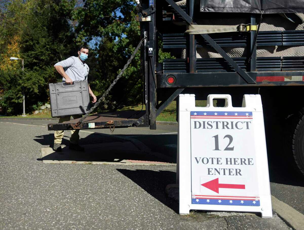 Public Works employee Victor Eimicke unloads a voting booth at the District 12 polling station at North Mianus School in the Riverside section of Greenwich, Conn. Monday, Nov. 1, 2021. Greenwich voters will head to the polls Tuesday to decide the positions of First Selectman, Tax Collector, Town Clerk, and Constable, as well as spots on the Board of Estimate and Taxation, Board of Education, Representative Town Meeting, and Board of Assessment Appeals.