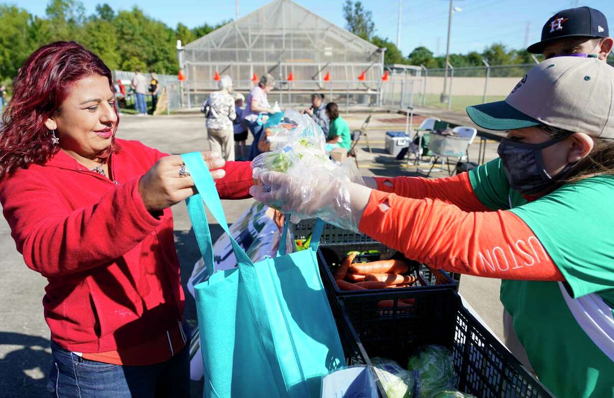 Roxana Sumrall, left, receives lettuce from Mia Gonzalez at the Environmental Community Advocates of Galena Park produce stand during a recent fall festival.