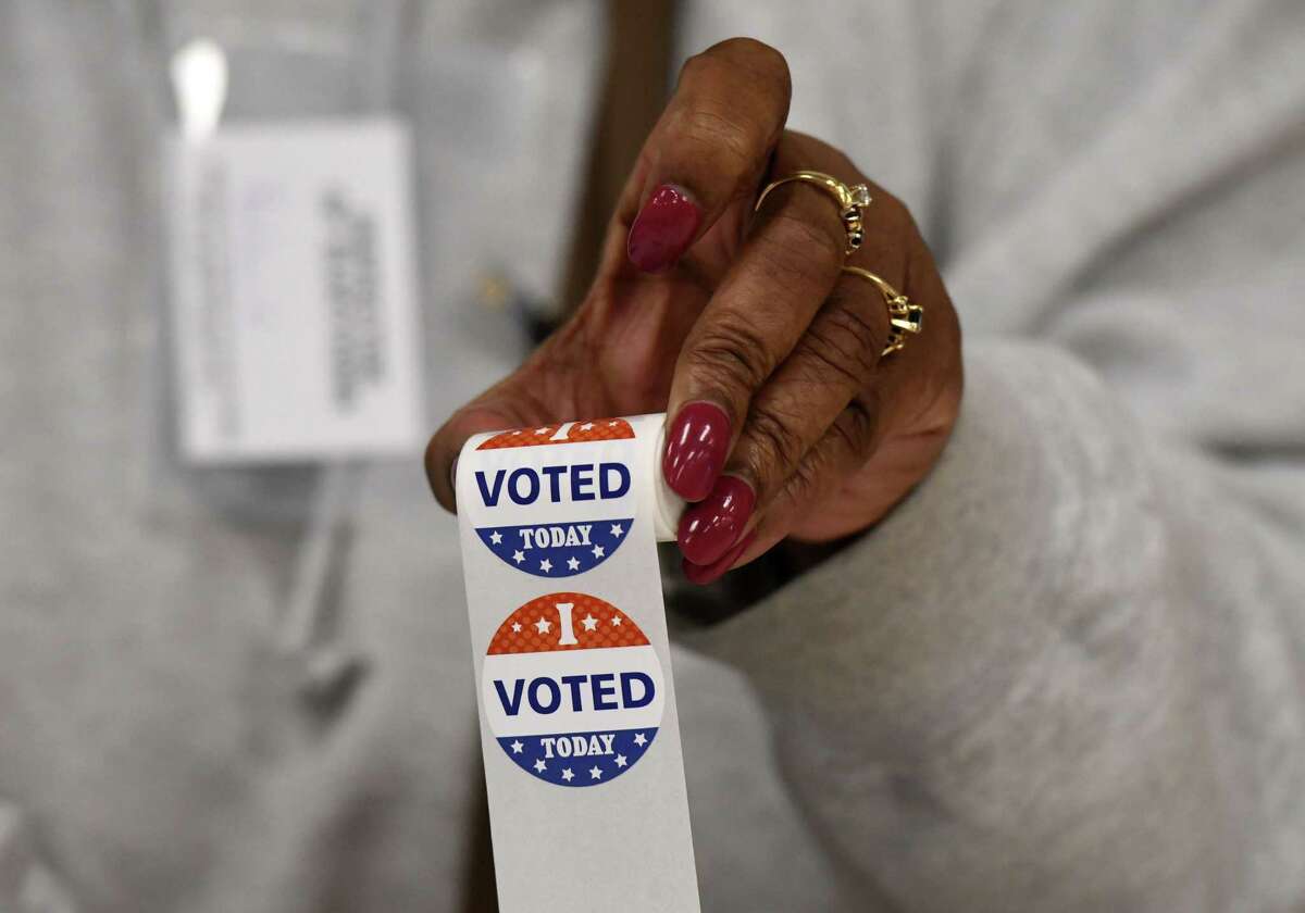 "I Voted" stickers are held up by a poll worker at the Ancient Order of Hibernians polling station on Tuesday, Nov. 2, 2021, on Ontario St. in Albany, N.Y.