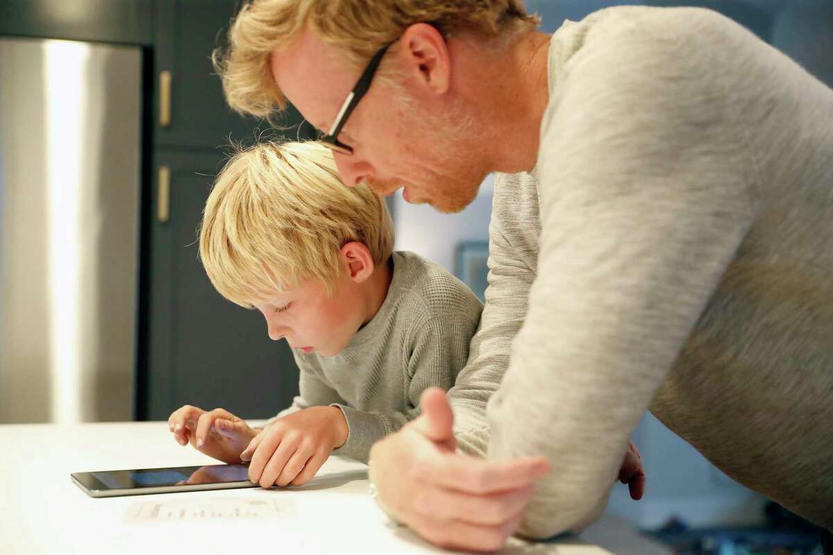 Charlie Wray, an internist at the San Francisco VA, helps his son, Brooks, 7, sign on to a tablet to do his homework at their home in Mill Valley in October. Charlie and his wife, Jennifer, are planning on getting Brooks vaccinated as soon as possible.