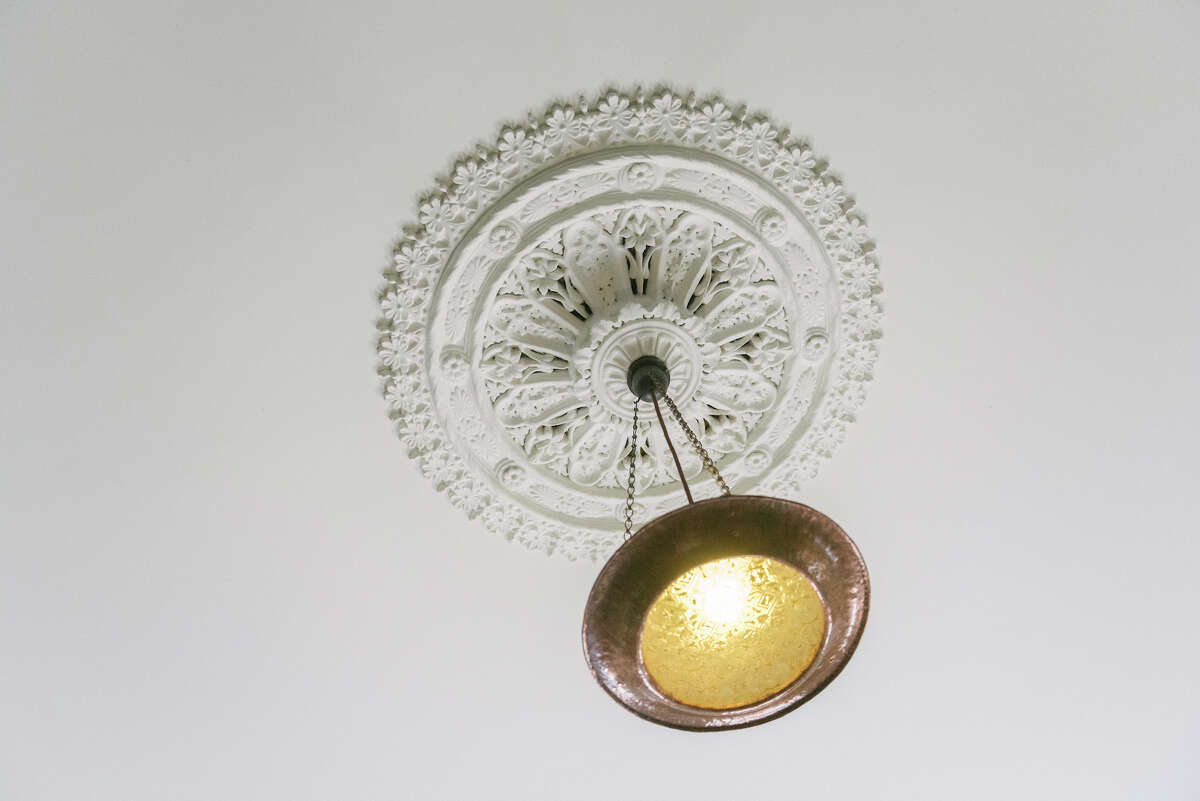 A plaster cast ceiling medallion in a Victorian home with a modern pendant light.