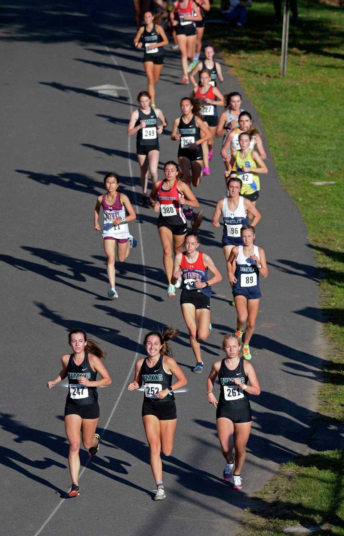 New Milford’s Claire Daniels (247), left, Sydney Kelleher (252) and Madelaine Sweeney (261) lead in the SWC girls varsity high school cross country championships on Oct. 20 at Bethel High School in Bethel.