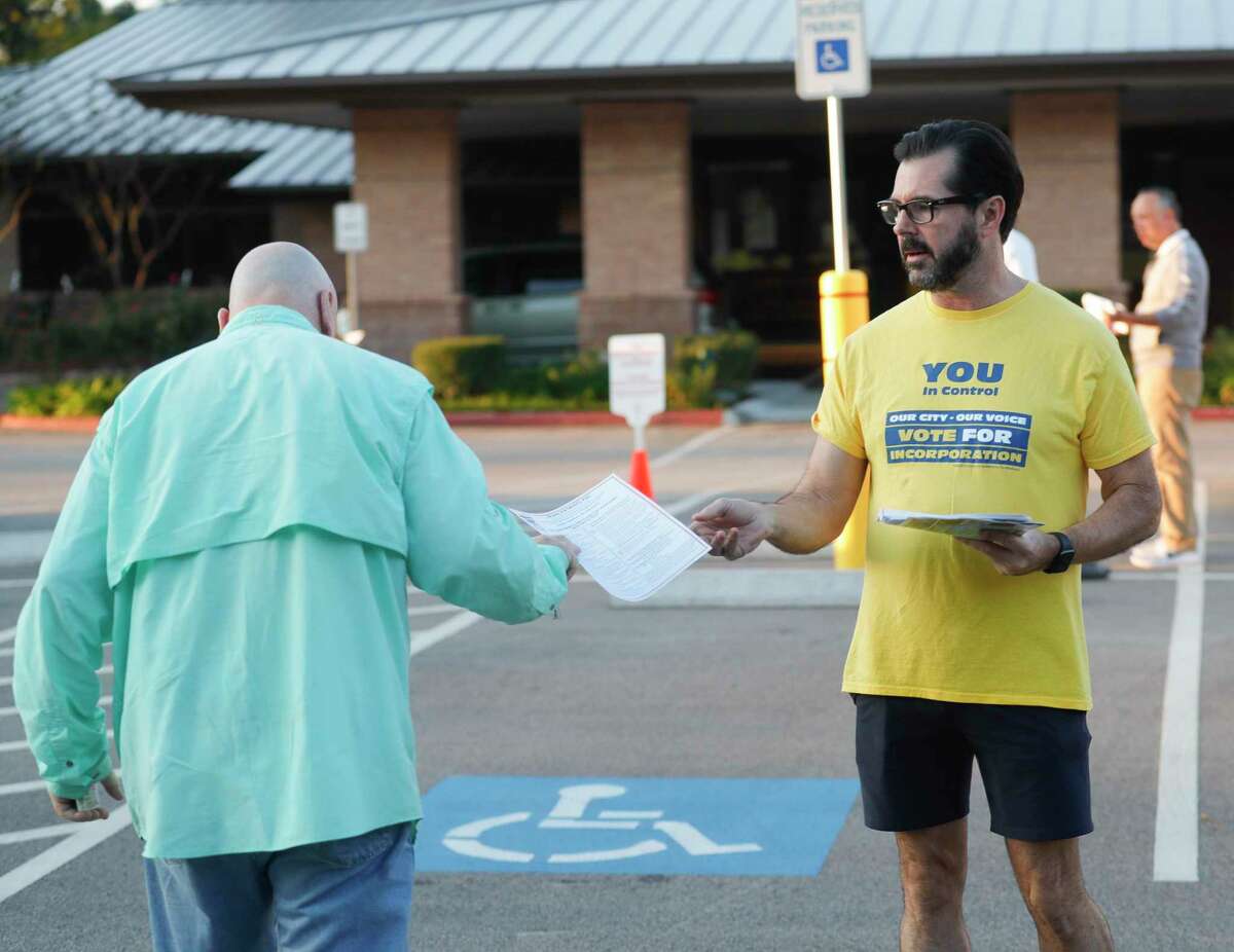 Alex Bunch hands out information to a man as voters take to the polls to decide whether or not The Woodlands should incorporation into a city, Tuesday, Nov. 2, 2021, in The Woodlands.