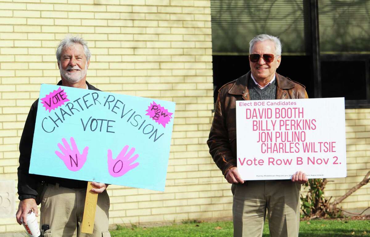Sebastian Giuliano, left, and a man encouraging residents to vote yes or no on two charter revision questions, outside Moody Elementary School Tuesday morning