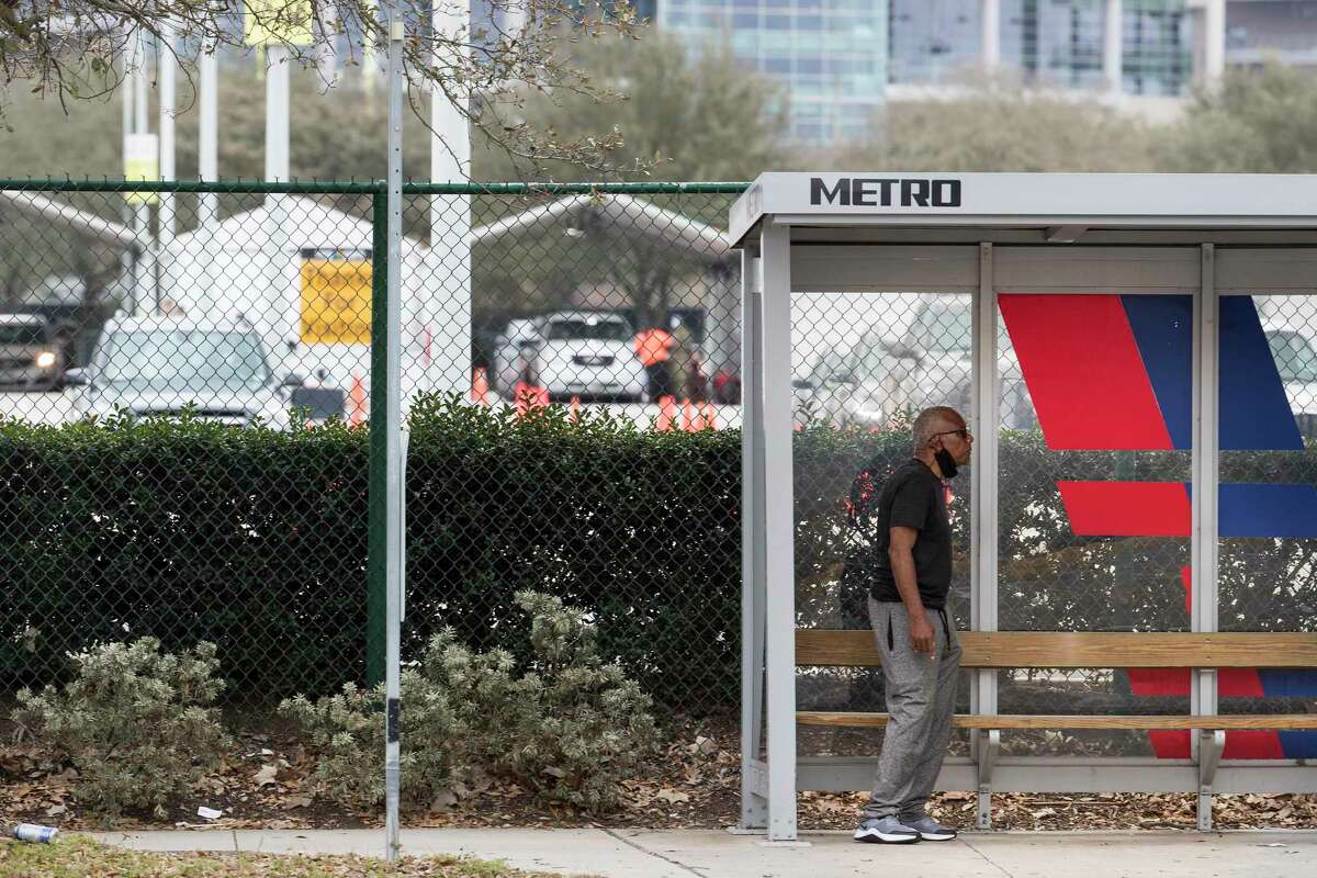 A man waits at a bus stop along Main Street next to the a Federal Emergency Management Agency COVID-19 vaccination super site at NRG Park Wednesday, Feb. 24, 2021 in Houston. The transit agency reported its 1,000 case of COVID among its employees and contractors this week.