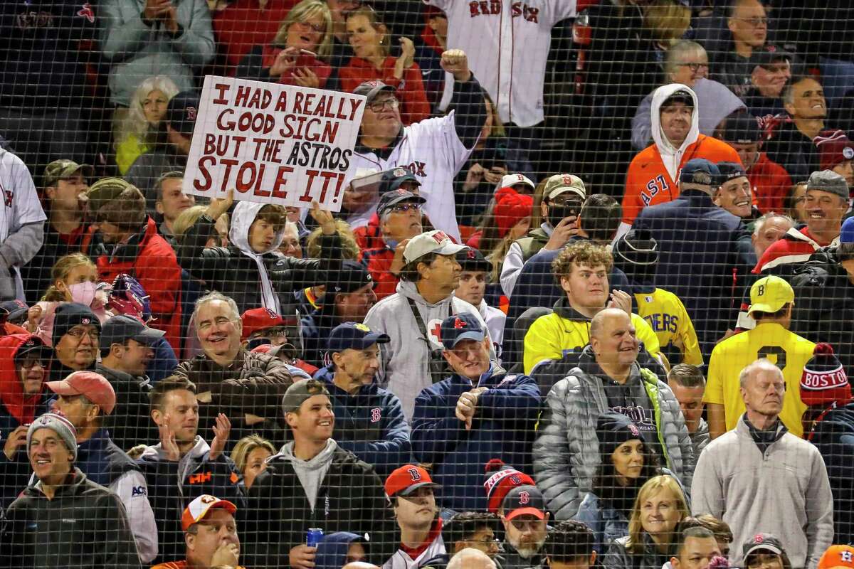 A young fan holds a sign referencing the Astros' sign stealing scandal during Game 3 of the American League Championship Series on Monday, Oct. 18, 2021, at Fenway Park in Boston.