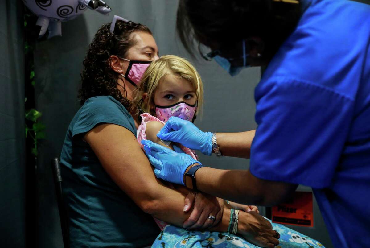 Kate Elsley holds daughter Piper Washburn, 6, about to receive her first dose of coronavirus vaccine at Emmanuel Baptist Church in San Jose. Elsley pulled her kids out of school when slots opened up.